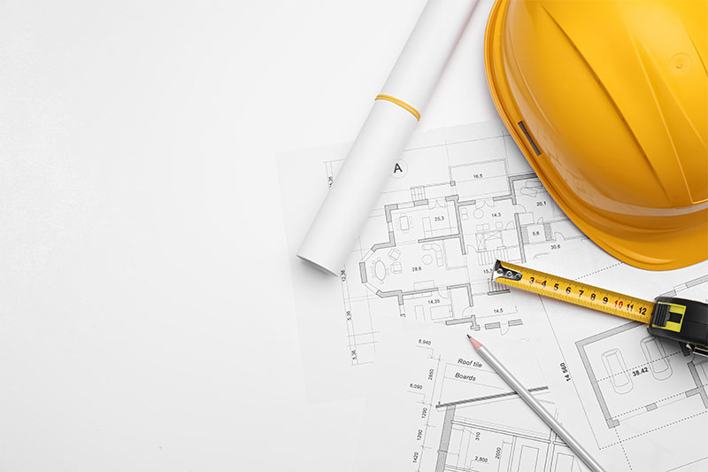 Hardhat, tape measure, and plans on desk